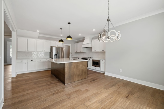 kitchen with premium range hood, a sink, stainless steel appliances, light wood finished floors, and light countertops