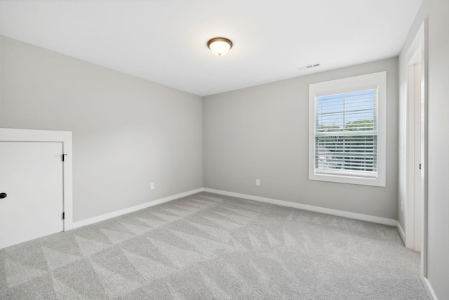 empty room featuring visible vents, baseboards, and light colored carpet