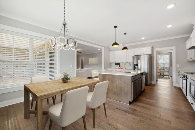 dining space featuring crown molding, dark wood-type flooring, sink, and a notable chandelier