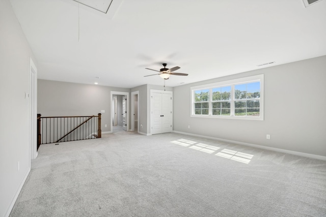 empty room featuring baseboards, light carpet, and attic access