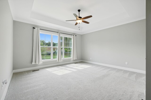 carpeted spare room with a tray ceiling and ceiling fan