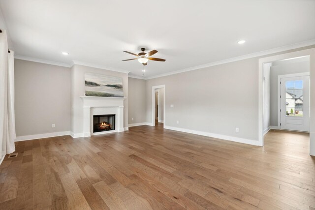 unfurnished living room with light wood-type flooring, ornamental molding, and ceiling fan