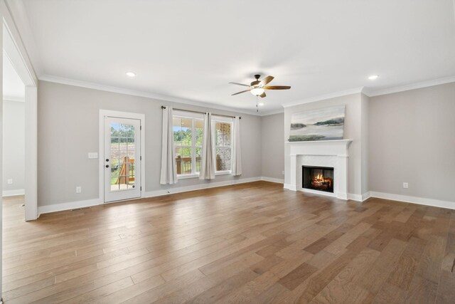 unfurnished living room with hardwood / wood-style floors, ceiling fan, a fireplace, and crown molding