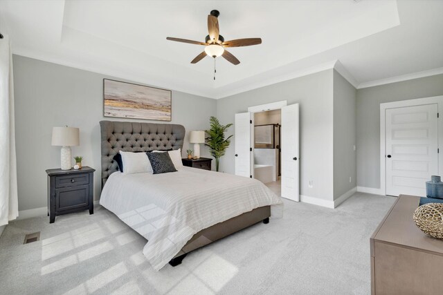 carpeted bedroom with crown molding, a raised ceiling, ensuite bathroom, and ceiling fan