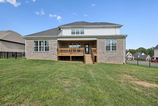 rear view of property featuring a yard, a deck, brick siding, and a fenced backyard