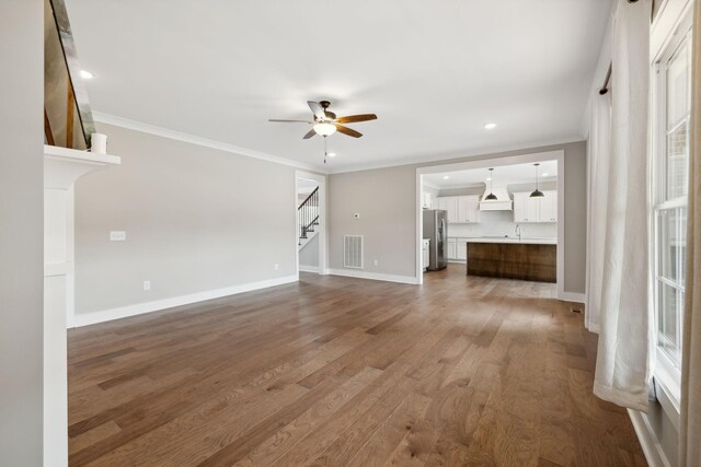 unfurnished living room with crown molding, wood-type flooring, and ceiling fan