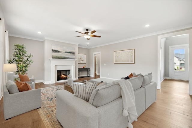 living room with ceiling fan, ornamental molding, and light hardwood / wood-style floors