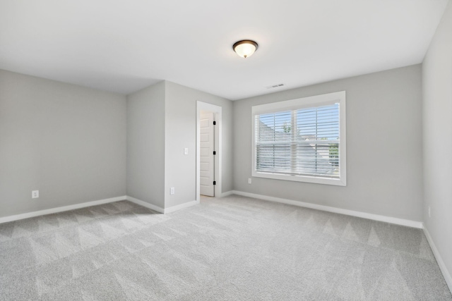 unfurnished room with visible vents, carpet, and baseboards