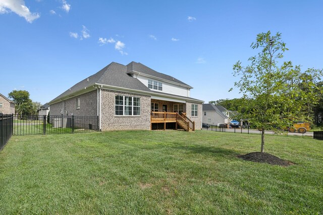 rear view of house featuring a deck and a lawn