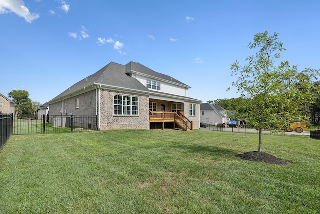 back of house featuring a deck, a lawn, brick siding, and a fenced backyard