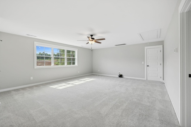 carpeted empty room featuring visible vents, baseboards, attic access, and a ceiling fan