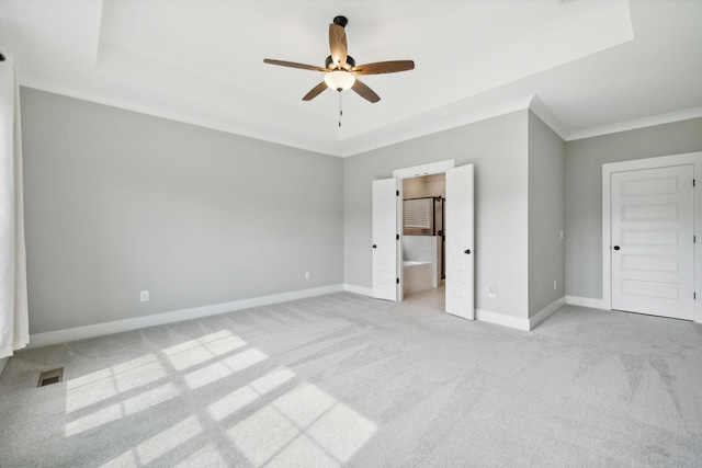 unfurnished bedroom with a tray ceiling, visible vents, baseboards, and light carpet