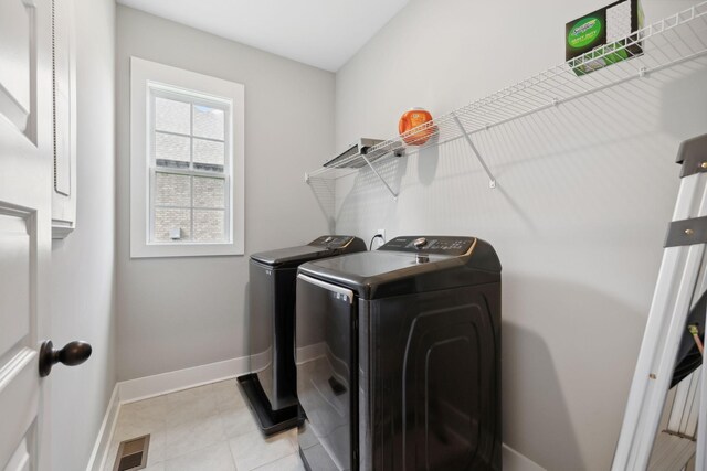 laundry area with light tile patterned floors and washer and dryer