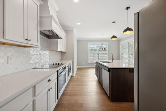 kitchen with backsplash, light countertops, appliances with stainless steel finishes, wood finished floors, and a sink