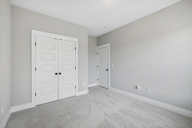 unfurnished bedroom with a closet and light colored carpet