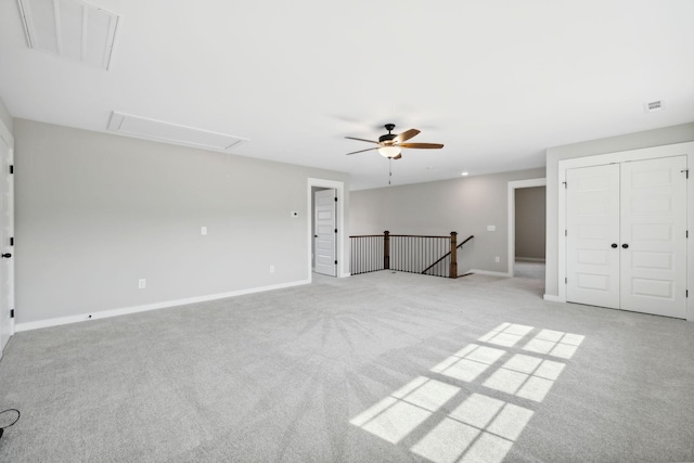 unfurnished bedroom featuring visible vents, baseboards, attic access, light carpet, and a ceiling fan