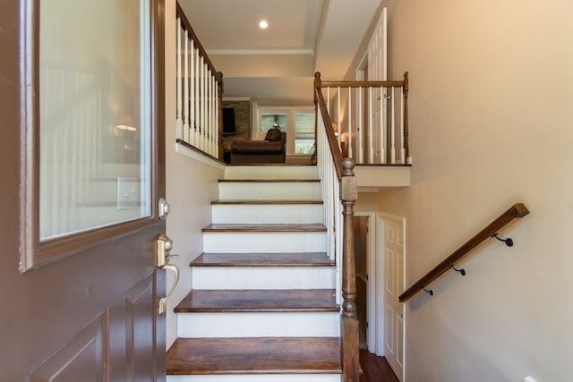 stairway with ornamental molding and wood-type flooring