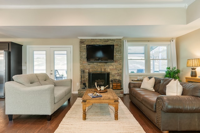 living room with crown molding, french doors, dark hardwood / wood-style flooring, and a stone fireplace