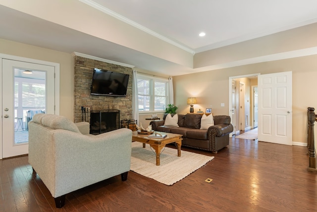 living room featuring crown molding, dark hardwood / wood-style flooring, plenty of natural light, and a stone fireplace