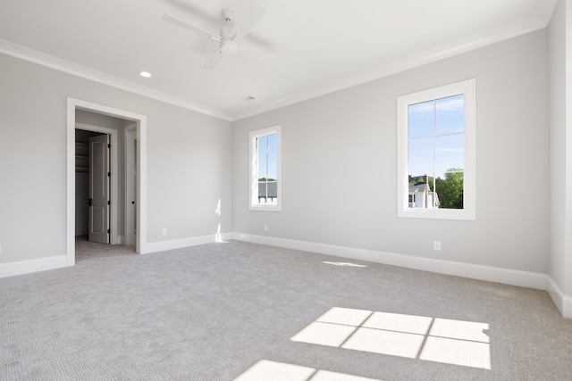 empty room with ceiling fan, light colored carpet, ornamental molding, and a healthy amount of sunlight