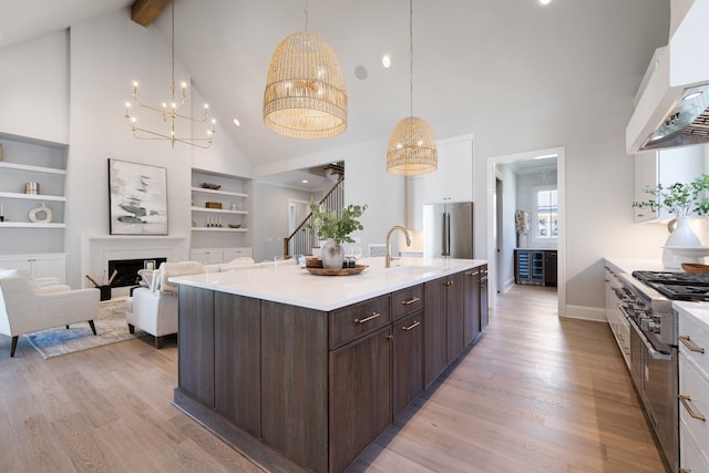 kitchen featuring an island with sink, light hardwood / wood-style floors, high vaulted ceiling, and high quality appliances