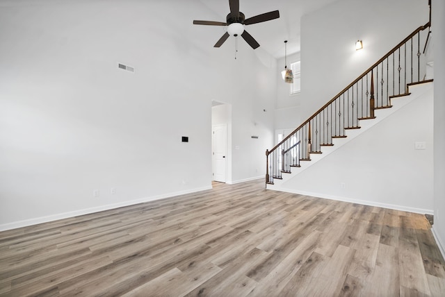 unfurnished living room featuring light hardwood / wood-style flooring, ceiling fan, and high vaulted ceiling