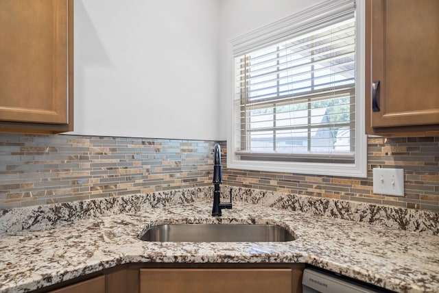 kitchen with light stone counters, a wealth of natural light, decorative backsplash, and sink