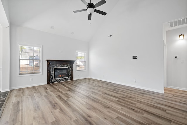 unfurnished living room with high vaulted ceiling, ceiling fan, a fireplace, and light hardwood / wood-style flooring