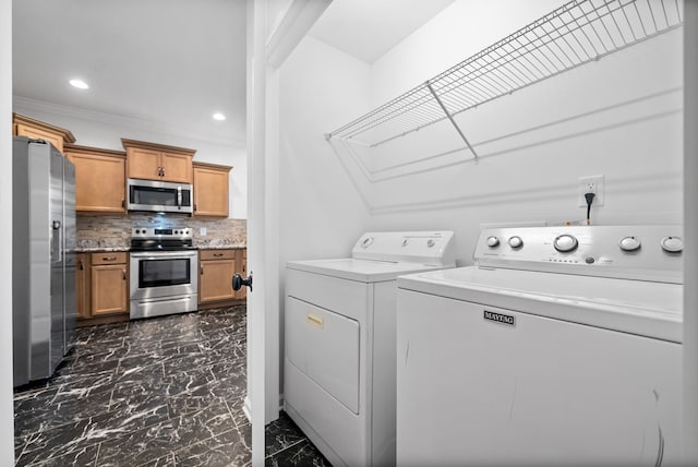 clothes washing area featuring crown molding and washing machine and clothes dryer