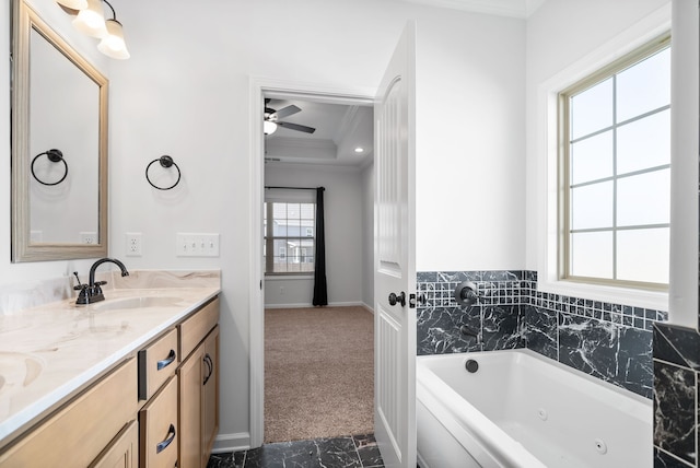 bathroom with ceiling fan, a tray ceiling, vanity, a bathtub, and ornamental molding