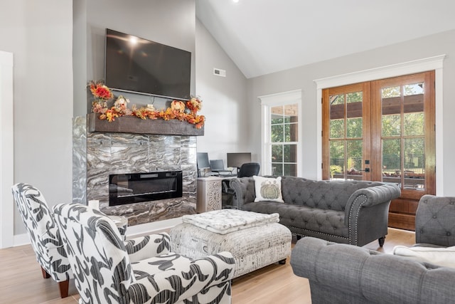 living room featuring light hardwood / wood-style flooring, high vaulted ceiling, and french doors