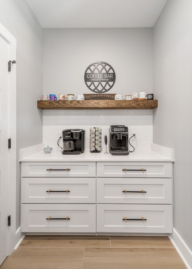 bar with white cabinets and light hardwood / wood-style flooring