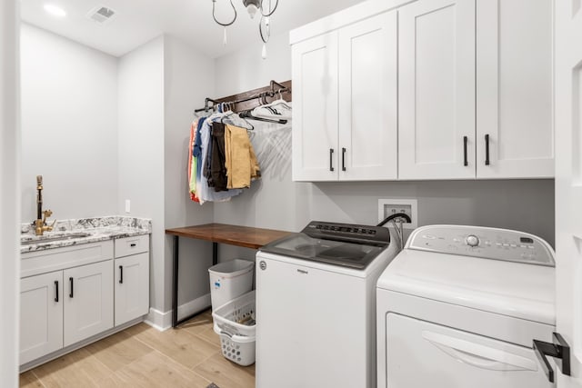 laundry area featuring separate washer and dryer, light wood-type flooring, cabinets, and sink