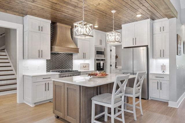 kitchen featuring custom range hood, an inviting chandelier, stainless steel appliances, and light hardwood / wood-style floors