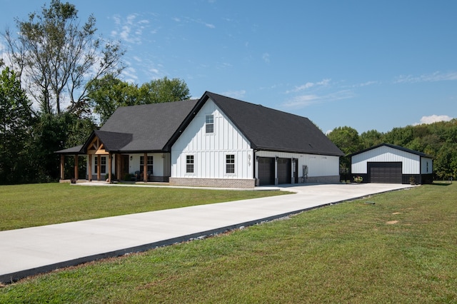 modern farmhouse with an outbuilding, a garage, a front lawn, and a porch