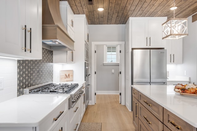 kitchen featuring light wood-type flooring, appliances with stainless steel finishes, wood ceiling, custom exhaust hood, and white cabinetry