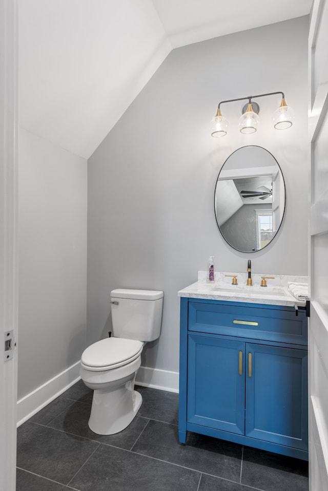 bathroom with tile patterned flooring, vanity, toilet, and vaulted ceiling