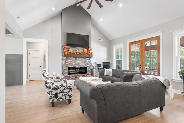 living room with a fireplace, high vaulted ceiling, light hardwood / wood-style flooring, and ceiling fan