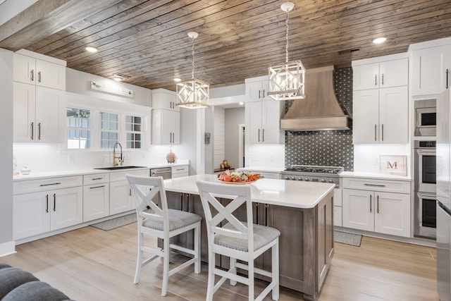 kitchen featuring a center island, a chandelier, premium range hood, and white cabinets