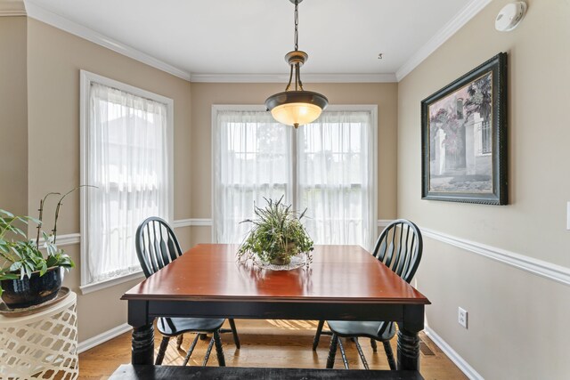 dining room with ornamental molding and light hardwood / wood-style floors