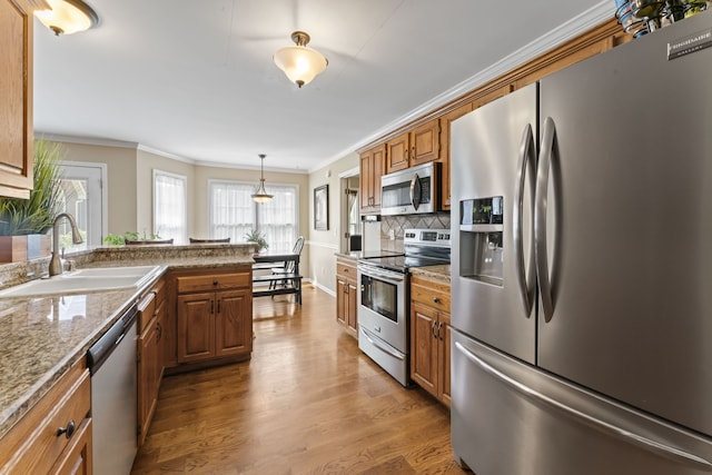 kitchen with light wood-type flooring, crown molding, sink, light stone countertops, and appliances with stainless steel finishes