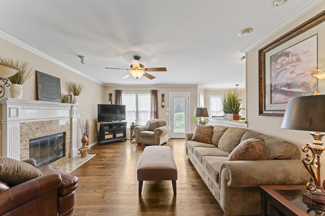 living room with crown molding, a premium fireplace, hardwood / wood-style flooring, and ceiling fan