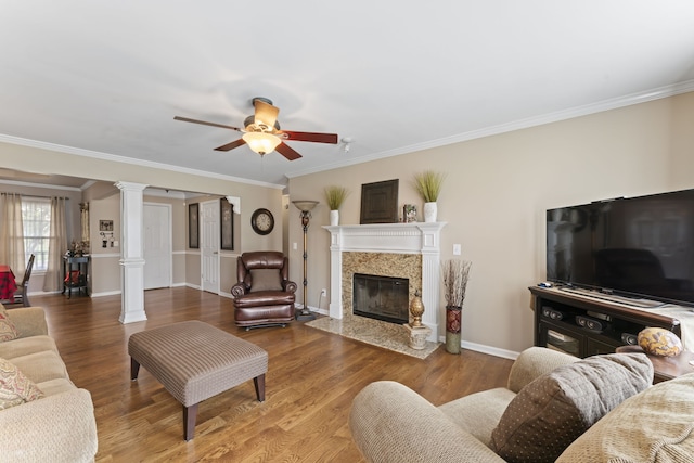 living room with ceiling fan, a fireplace, decorative columns, and wood-type flooring