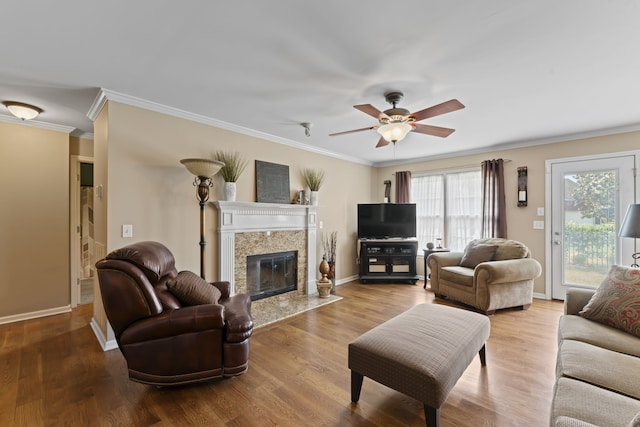 living room featuring a fireplace, ornamental molding, hardwood / wood-style flooring, and ceiling fan