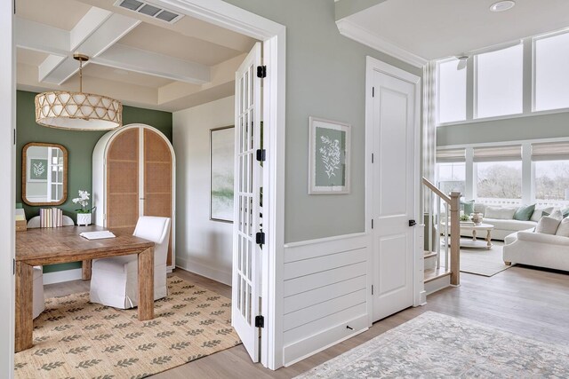 foyer with beamed ceiling, coffered ceiling, and light hardwood / wood-style flooring