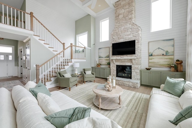 living room with a towering ceiling, a healthy amount of sunlight, and light wood-type flooring