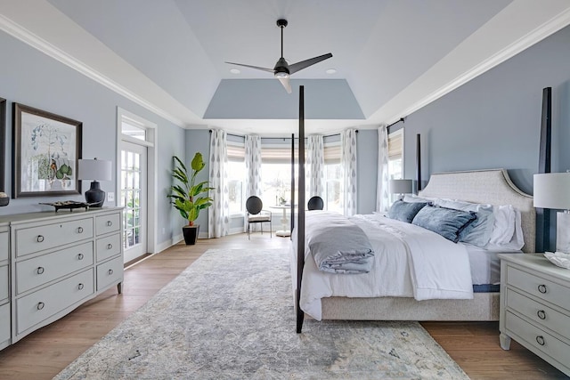 bedroom featuring lofted ceiling, crown molding, ceiling fan, light hardwood / wood-style floors, and a raised ceiling