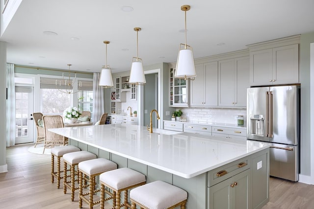 kitchen featuring pendant lighting, high end fridge, sink, and a large island with sink