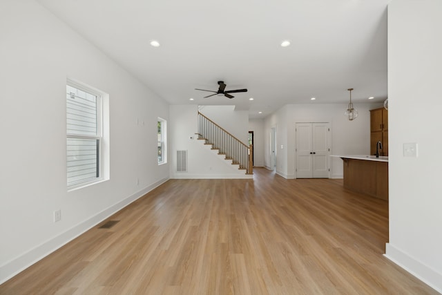 unfurnished living room with ceiling fan, sink, and light hardwood / wood-style floors