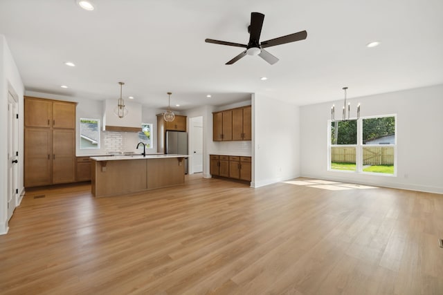 kitchen with ceiling fan with notable chandelier, light hardwood / wood-style floors, plenty of natural light, and hanging light fixtures